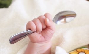 赤ちゃんの手がスプーンを握っている写真