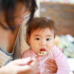 お母さんが赤ちゃんにご飯を食べさせている画像